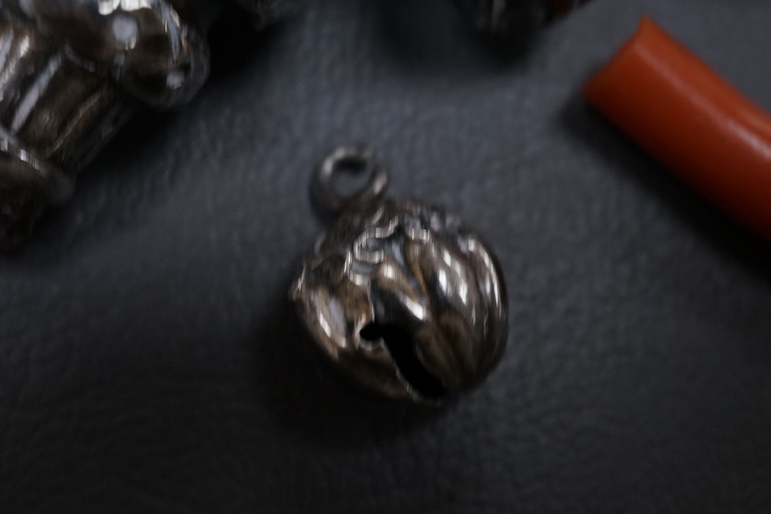 A late Victorian silver child's rattle, with four (ex five) bells and damaged coral teether, Colen Hewer, Cheshire, Birmingham, 1890, 78mm without the coral.